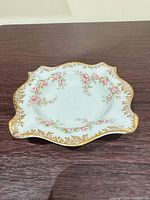 Top view of scalloped trinket dish showing floral pattern and gold trim