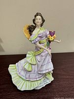 Front view of figurine in lavender dress with green bow holding flowers