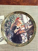 Front view of decorative plate showing artwork, gold border, and artist signature