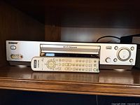 Front view of Sony silver SLV-series VHS VCR with remote placed in cassette slot