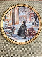 Front view of decorative plate showing winter scene and gold border