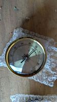 Analog hygrometer face with brass bezel and compass rose scale