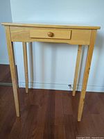 Front view of light wood side table showing drawer and legs