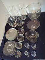 Overhead view of entire assortment showing two hurricane vases, stemware, trifle bowl, handled bowl, compote, and stack of plates