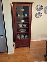 Left cabinet showing glass door, shelves, drawer