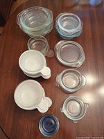 All twelve glass storage bowls laid out showing variety of sizes, colors and lids