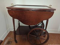 Right-side view showing glass-top tray, drop leaf, spoke wheels and casters
