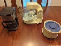 Three kitchen appliances: Sunbeam stand mixer, Krups coffee maker, Rival Crockette