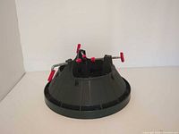 Overall view of plastic and metal stand showing three red screw clamps and circular base