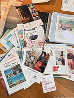 Overview of loose magazine ad pages spread out and binder with sleeved ads visible