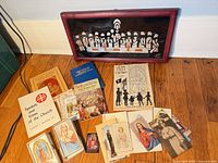 Overview of framed Last Supper art with assorted booklets, pamphlets, holy cards and boxed sets spread on floor