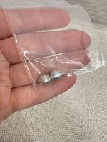 Two loose pearls inside small clear plastic bag