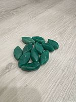 Group of 11 green marquise beads on wood surface