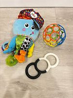 Plush octopus toy, Oball sensory ball and dual-ring teether on floor