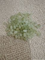 Pile of light green oval jade beads on fabric background
