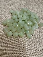 pile of light green faceted beads on fabric background