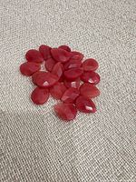 Pile of red faceted teardrop beads on fabric surface