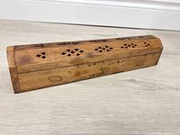 Closed wooden incense burner box showing brass inlays and carved lid ventilation holes