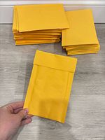 Stacked yellow padded mailers and single mailer front view