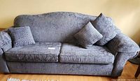 Front view of gray patterned 3-seat sofa with two throw pillows