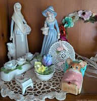 Shelf with porcelain figurines, floral ceramics, lace and headband