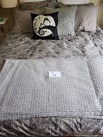Throw laid across bed with pillowcases and decorative pillows visible