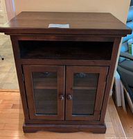 Front view of entire dark brown pine media cabinet with glass doors and open shelf