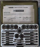 Open metal case showing taps, dies, wrench, die stock and manuals