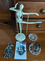 Overview: bracelet on card, glass ring dishes, earrings, black seed bead necklace, silver chains on mannequin