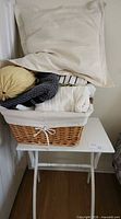 Overall lot showing pillows piled in wicker basket on side table