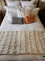 Full bed showing queen bedspread, knit throw, multiple decorative pillows and shams