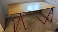 Full view of table showing veneer top and red metal sawhorse legs