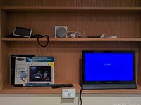 Shelf view with boxed Belkin screen protector, Vizio TV, remote, small devices