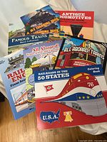 Stack of eight train-themed coloring and activity books showing all titles