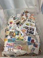 Overview of plastic bin filled with loose and on-paper stamps