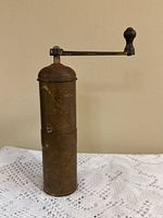 Full view of standing brass coffee grinder showing handle and body