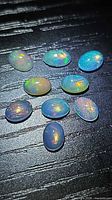 Ten oval opals on black background showing colour play