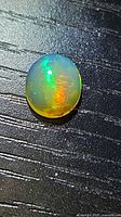 Top view of oval opal showing vivid green and orange play-of-colour