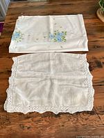 Tablecloth folded showing blue floral print; crocheted-edge placemat laid flat
