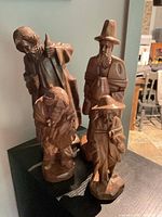 All four carved wood figurines shown together