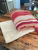 Rolled striped blanket atop solid cream blanket on table