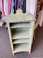 Front view showing four shelves and distressed green and cream paint