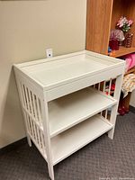 Full view of white wood changing table showing two shelves and raised changing top