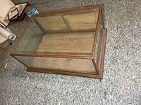 Full view of oak framed glass display case, showing front, top, and base