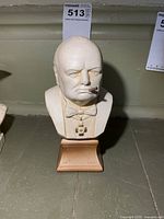 Front view of plaster bust showing Churchill’s face, attire, and pedestal