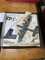 Box with die-cast bomber, base, loose props and wheels
