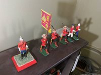 Six painted metal soldiers on shelf