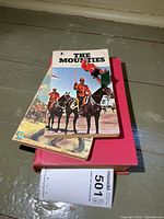 Stack of three RCMP books – two paperbacks, one red hardcover