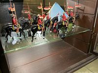 Five painted metal RCMP cavalry figures on glass shelf