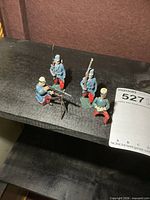 All four painted metal soldier figurines on shelf
